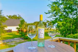 a bottle of wine and two wine glasses on a table at Luxe Dream Beach House in Gulfport
