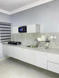 a white kitchen with a sink and a counter top at Legacy apartments in Ikeja +5 photos