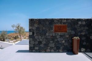 a stone wall with a sign on top of a building at Thimari Lodge in Fira