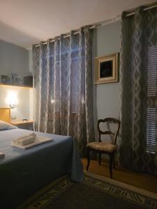 a bedroom with a bed and a chair and a window at L'Albore in Costigliole Saluzzo