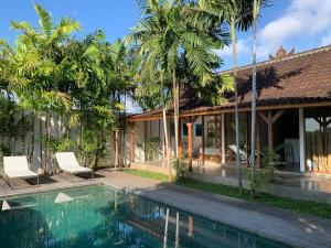 a villa with a swimming pool and palm trees at Villa YAMI Uluwatu Private Infinity Pool Jungle Views in Ungasan