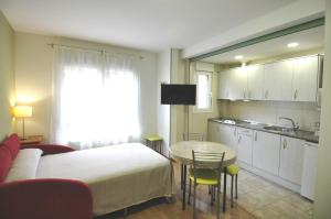 a room with a bed and a table and a kitchen at Hotel Apartamentos Aralso in Segovia