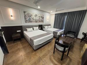 a hotel room with two beds and a table at HOTEL SNR AURORa in Guntūr