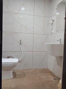 a white bathroom with a toilet and a shower at HOTEL SNR AURORa in Guntūr +9 photos