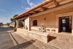 Una vista exterior de una casa con una mesa y sillas. en Finca Hort De Sa Barrala, en Ses Covetes