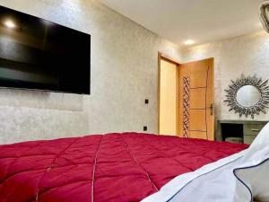 a bedroom with a large red bed with a flat screen tv at Las Brisas Beachfront Mekad private in Oued Laou