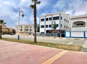 an empty street with a white building and palm trees at Las Brisas Beachfront Mekad private in Oued Laou