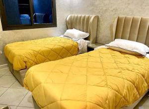 two beds in a room with yellow blankets at Las Brisas Beachfront Mekad private in Oued Laou