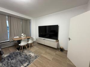 a living room with a table and a large flat screen tv at Downtown in Bonn