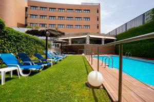 a row of blue lounge chairs next to a swimming pool at Hotel Reston Valdemoro in Valdemoro