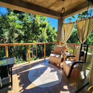 a screened in porch with two chairs and a table at Studio Mata dos Curiós in Petrópolis