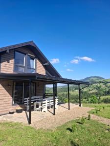 a house with benches and a view of the mountains at Bukhouse Carpathians in Krivorovnya