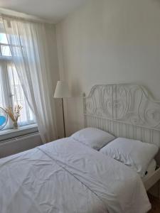 a white bed in a white bedroom with a window at Romantische kamer nabij centrum in Eindhoven