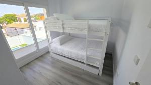 a white bunk bed in a room with a window at Chalet Laguna Place in Chipiona +11 photos