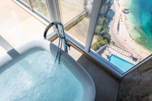 a bath tub in a room with a view of a beach at Nuna Hotel & Apartments in Vlorë