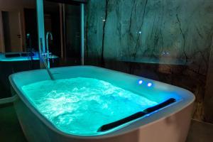 a bath tub filled with blue water in a bathroom at Nuna Hotel & Apartments in Vlorë