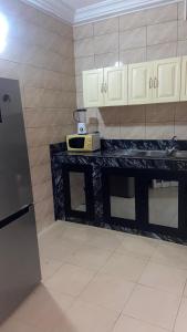 a kitchen with a black counter and white cabinets at New ACROPOLE in Komé