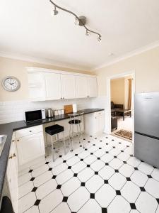 a kitchen with white cabinets and a black and white tiled floor at Spacious 2 bedroom apartment near Wembley stadium with free parking in London