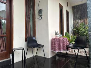 two black chairs and a table with a table cloth at Hansel Homestay in Batu