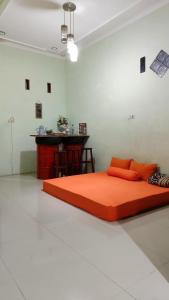an orange bed in a white room with a table at Hansel Homestay in Batu