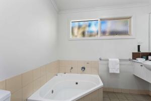 a white bathroom with a tub and a window at The Point Villa in Cowes +7 photos