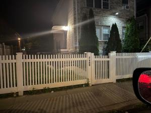 a white fence in front of a house at night at SEVENeCOZY in Edgemere
