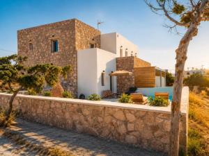a house on the beach with a stone wall at Milea amare Suites in Adamantas