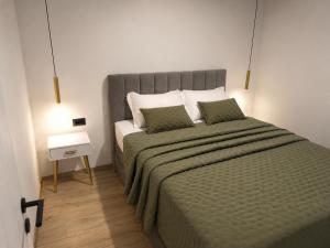 a bedroom with a large bed with two green pillows at Apartments Villa Nikola- one minute to the beach in Gradac