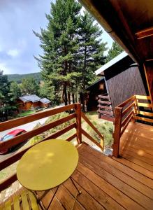 a wooden deck with a yellow table and a fence at Chalet Des Oursons, Capcir Pyrénées Catalanes in Puyvalador