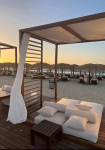 a bed on a deck with chairs and umbrellas on the beach at GAIA Penthouse in El Dab‘a
