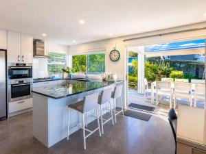 a kitchen with a large island with bar stools at Bella Seven- Stay Waiheke in Oneroa