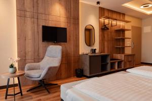 a bedroom with a bed and a chair and a television at Hotel Aleksandrija in Ohrid