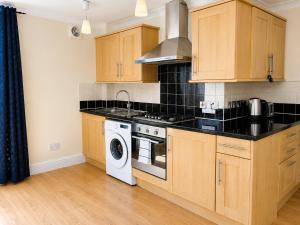 a kitchen with wooden cabinets and a washing machine at Spacious flat in Streatham in London