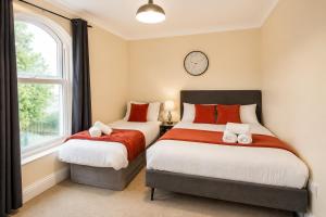 two beds in a bedroom with a clock on the wall at Spacious flat in Streatham in London