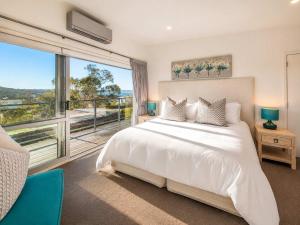 a bedroom with a white bed and a large window at Bella Seven- Stay Waiheke in Oneroa