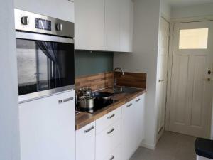 a kitchen with white cabinets and a sink at Historic Cottage w Garden in Breskens