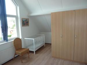 a room with a cabinet and a chair and a crib at Bungalow in Breskens near Beach & Lighthouse in Breskens +16 photos