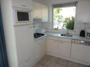 a kitchen with white cabinets and a sink and a window at Bungalow in Breskens near Beach & Lighthouse in Breskens