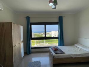 a bedroom with a bed and a large window at GAIA Penthouse in El Dab‘a