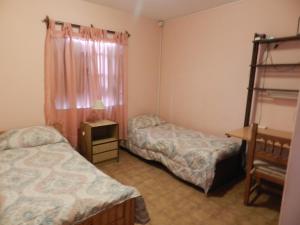 a room with two beds and a table and a shelf at Lo de Lili in Puerto Madryn