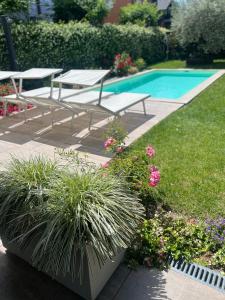 a garden with benches and a swimming pool with flowers at VILLA LIDO - Lake Como in Colico