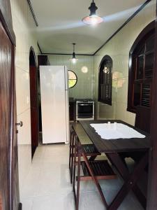 a kitchen with a table and a white refrigerator at Encanto da Serra casa 1 in Miguel Pereira