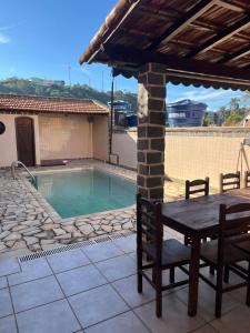 a patio with a table and chairs next to a swimming pool at Encanto da Serra casa 1 in Miguel Pereira
