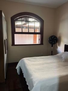 a bedroom with a white bed and a window at Encanto da Serra casa 1 in Miguel Pereira +14 photos