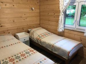 two beds in a room with wooden walls and windows at ALVORADA Mościce Dolne nad Bugiem in Nowosiółki