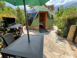 a table with an umbrella next to a grill at Glamping Green Garden Suite in Villa de Leyva