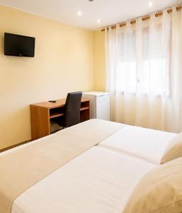 a bedroom with two beds and a desk with a computer at Hostal La Tina in Port de la Selva