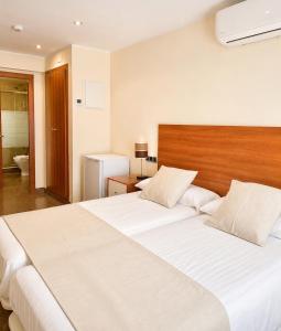 a bedroom with a large white bed with a wooden headboard at Hostal La Tina in Port de la Selva