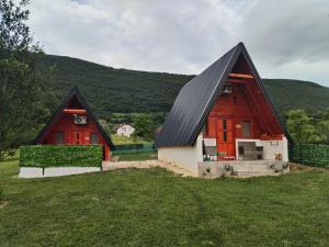 two barns with black roofs on a green field at Adna 's Home in Orašac