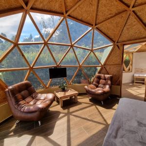 a room with two leather chairs and a large window at Glamping Green Garden Suite in Villa de Leyva